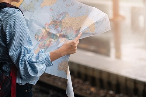 Matkustaja pitelee käsissään suurta paperista karttaa, jossa näkyy Suomi